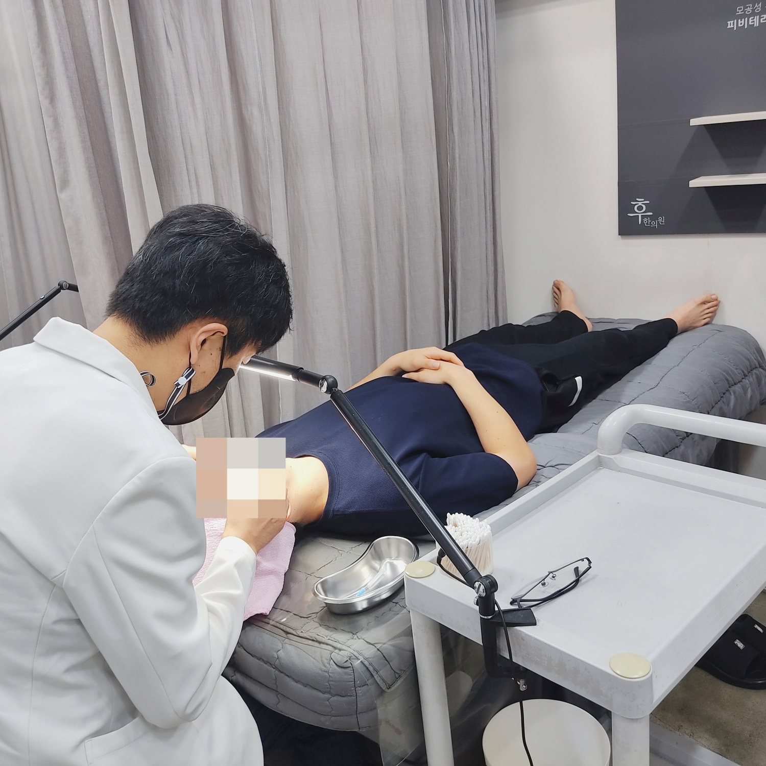 누운 환자의 얼굴을 살피며 진행하는 시술 장면